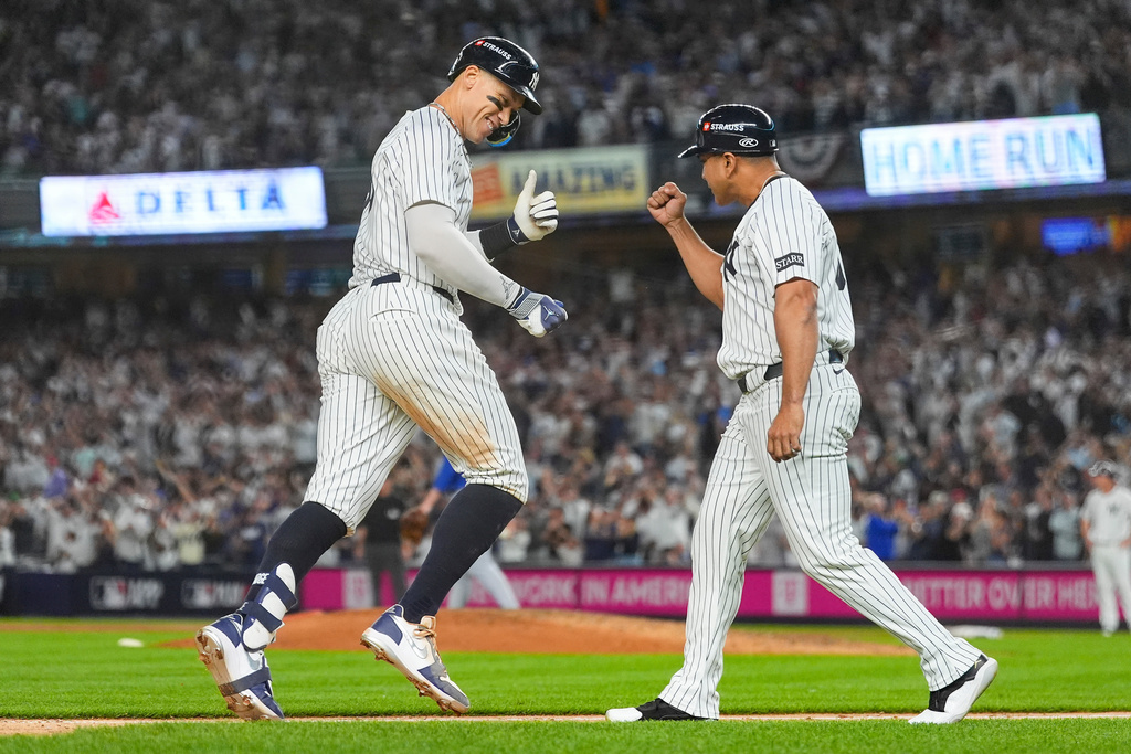 New York Yankees' Aaron Judge celebrates with third base coach Luis Rojas after hitting a three-run home run against the Toronto Blue Jays during the fourth inning of Game 3 of baseball's American League Division Series, Tuesday, Oct. 7, 2025, in New York. (AP Photo/Yuki Iwamura)