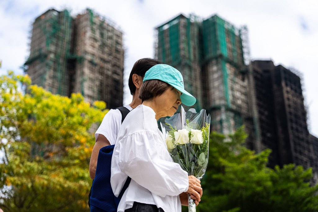 People offer flowers for the victims near the site of a deadly fire at Wang Fuk Court, a residential estate in the Tai Po district of Hong Kong's New Territories on Tuesday, Dec 2, 2025. (AP Photo/Chan Long Hei)