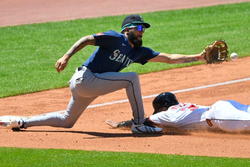 Seattle Mariners third baseman J.P. Crawford, top, reaches for the ball before tagging out Cleveland Guardians' Kahlil Watson, bottom, during the fourth inning of a baseball game, Sunday, June 28, 2026, in Cleveland. (AP Photo/David Richard)