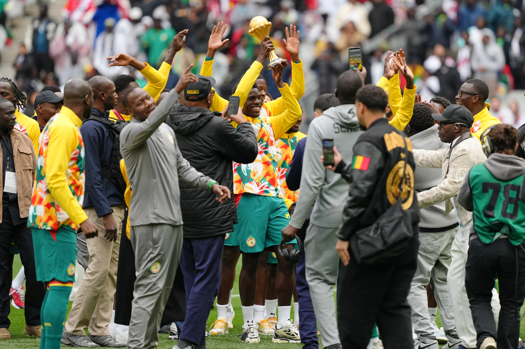 Senegal players celebrate with the Africa Cup of Nations trophy ahead of the international friendly soccer match between Senegal and Peru in Saint-Denis, outside of Paris, Saturday, March 28, 2026. (AP Photo/Aurelien Morissard)