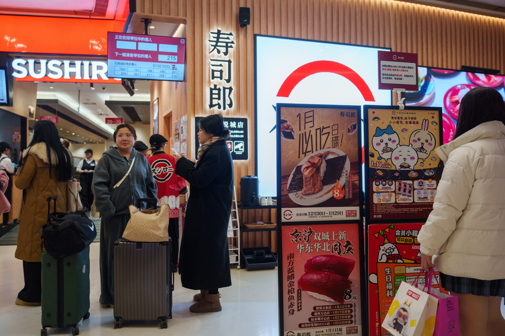 Customers wait outside a store for Sushiro, a Japan-based conveyor-belt sushi chain, in Beijing, Wednesday, Jan. 14, 2026. (AP Photo/Vincent Thian)
