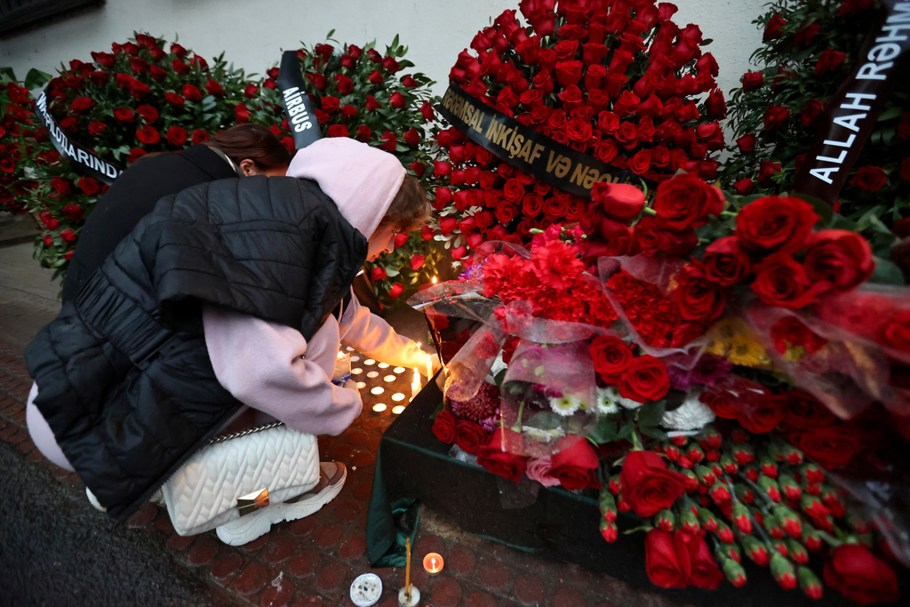 FILE - A woman lights candles at the wall of the apartment building in Baku, Azerbaijan, Dec. 28, 2024, in memory of pilot Alexander Kalyanin, who died in the crash of an Azerbaijan Airlines jet near the Aktau, Kazakhstan, airport. (AP Photo, File)