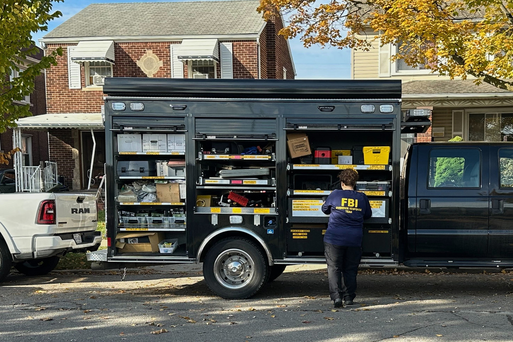 An FBI agent stands by an Evidence Response Team truck outside a home in a Dearborn, Mich., neighborhood on Friday, Oct. 31, 2025. (AP Photo/Mike Householder)