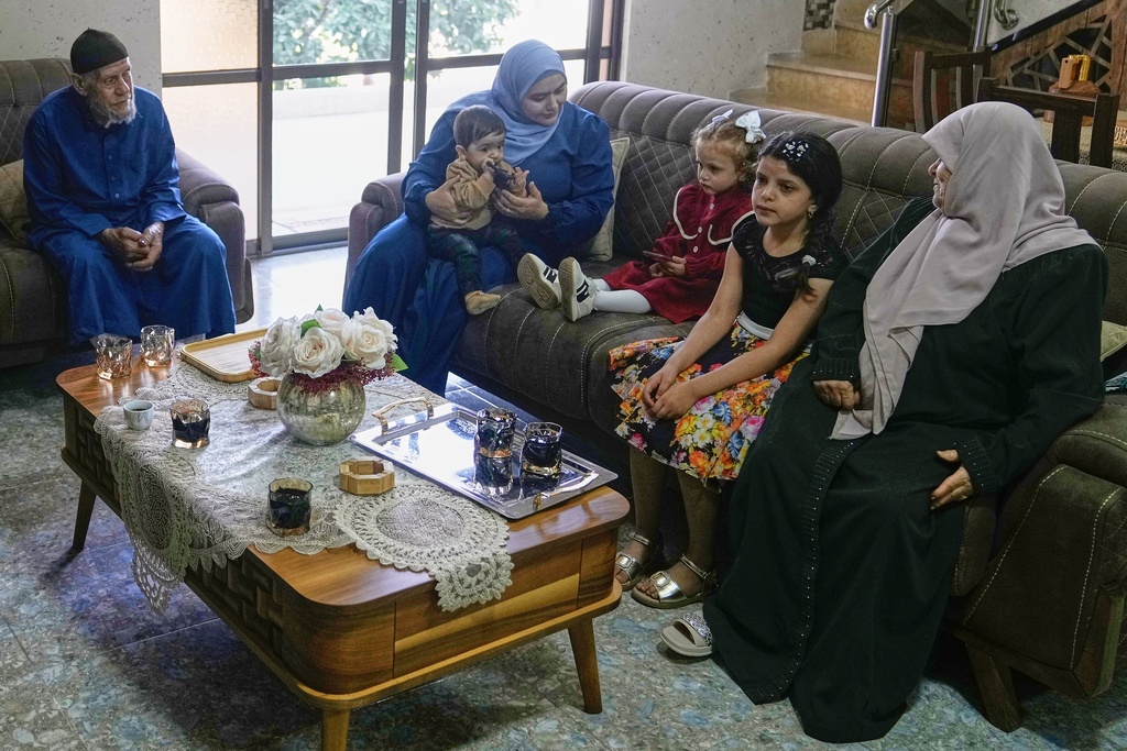 Relatives of Mohammad Husein Ali, 45, who died in the Israeli Kishon detention center, sit in their living room in the Nur Shams refugee camp near the West Bank town of Tulkarem, Thursday, Oct. 23, 2025. From left are Mohammad’s father Waleed Husein Ali, wife Hadeel, son Bara’, daughter Misk, an unidentified relative, and Mohammad’s mother Sobheya Husein Ali. (AP Photo/Majdi Mohammed)