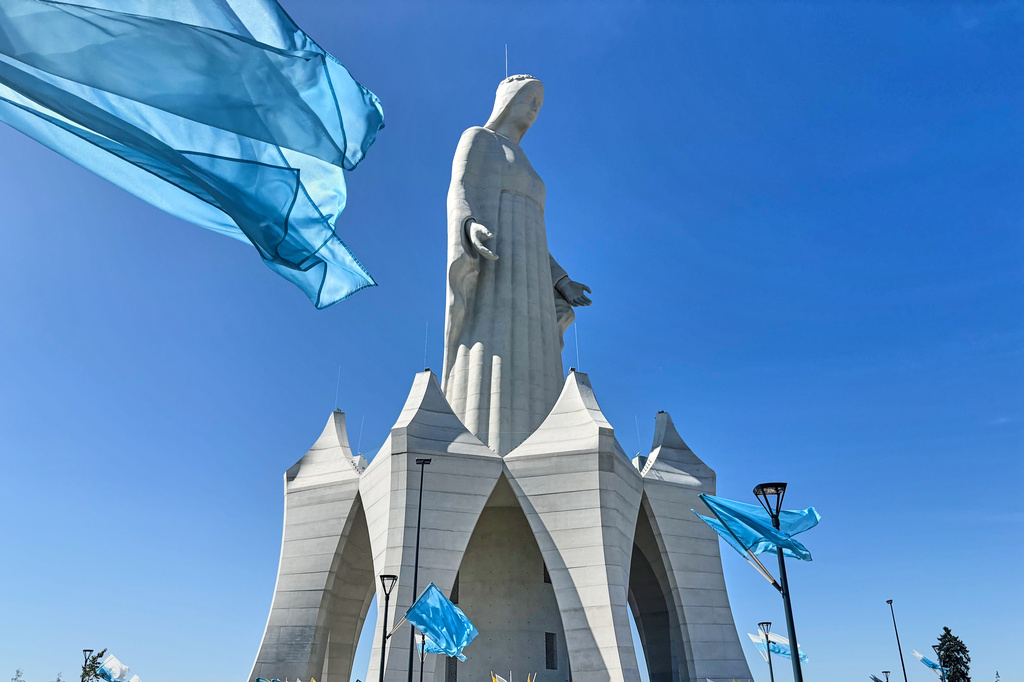 Flags wave in the wind in front of an enormous statue of the Virgin Mary that is believed to be Europe's tallest during the inauguration in the village Konotopie, Poland, Saturday, Aug. 15, 2026. (AP Photo/Claudia Ciobanu)
