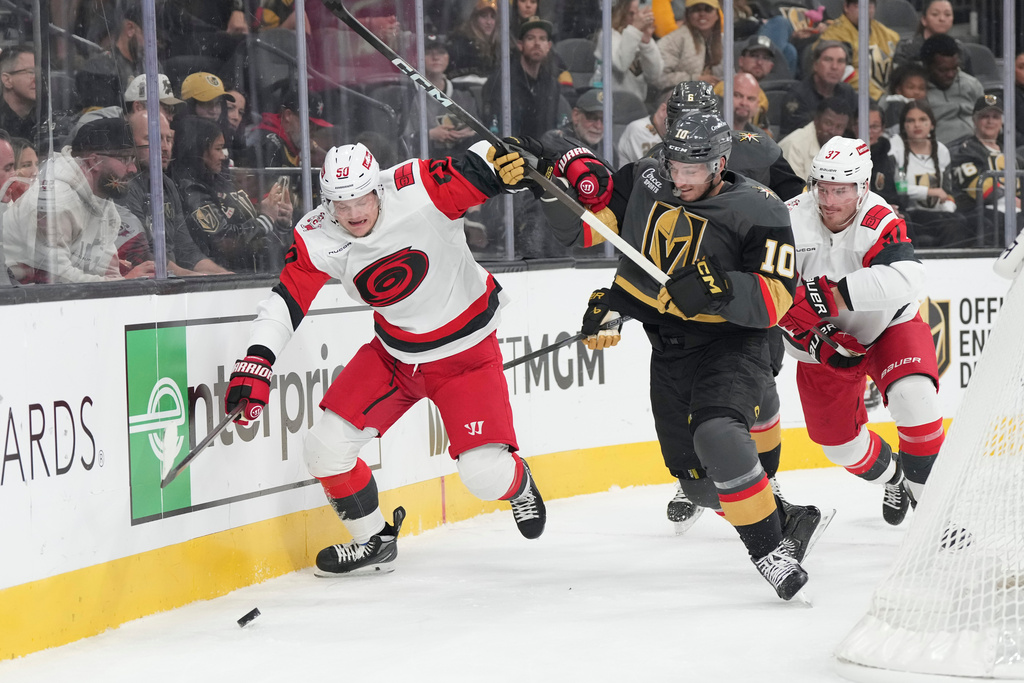 Carolina Hurricanes left wing Eric Robinson (50) and Vegas Golden Knights center Colton Sissons (10) battle for the puck during the first period of an NHL hockey game Monday, Oct. 20, 2025, in Las Vegas. (AP Photo/Candice Ward)