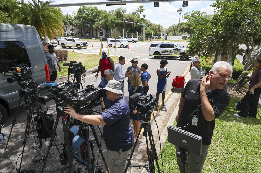 Members of the media document detectives and deputies with the Hillsborough County Sheriff's Office as they investigate inside the Lake Forest subdivision of Tampa, Fla., on Friday, April 24, 2026, where authorities said a man was taken into custody after barricading himself inside a home, in connection to the search for two missing University of South Florida graduate students. (Douglas R. Clifford/Tampa Bay Times via AP)