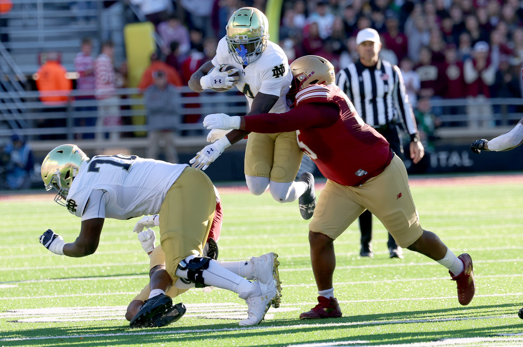 Notre Dame running back Jeremiyah Love, center, is grabbed and tackled by Boston College defensive lineman Kwan Williams, right, during the first half of an NCAA college football game Saturday, Nov. 1, 2025 in Boston. (AP Photo/Mark Stockwell)
