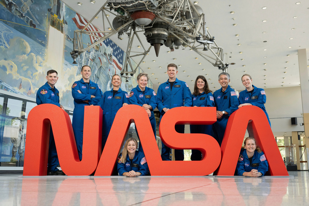 In this undated photo released by NASA, NASA's 10 newest astronauts pose behind the logo at at NASA’s Johnson Space Center in Houston, Texas. Left to right; Sept. 22, 2025. The 10 candidates, pictured here at NASA’s Johnson Space Center in Houston. U.S. Army CW3 Ben Bailey, U.S. Air Force Maj. Cameron Jones, Katherine Spies, Anna Menon, U.S. Navy Lt. Cmdr. Erin Overcash, U.S. Air Force Maj. Adam Fuhrmann, Lauren Edgar, Yuri Kubo, Rebecca Lawler, and Dr. Imelda Muller. (NASA via AP)