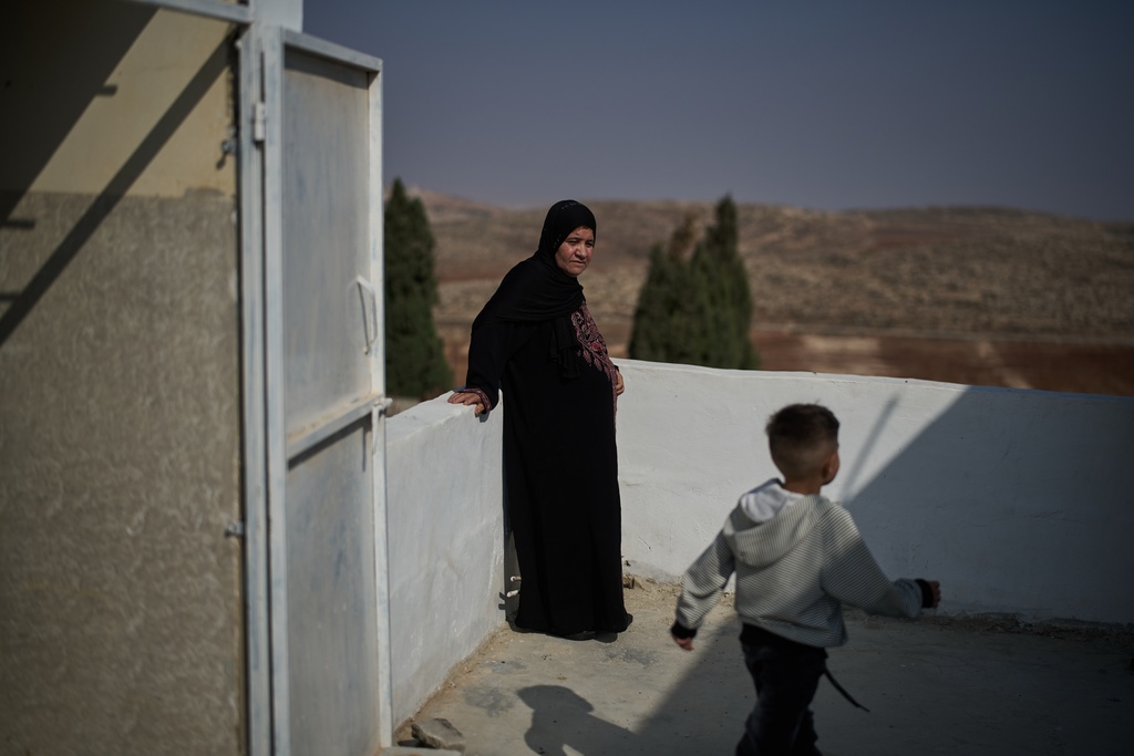 Palestinian Afaf Abu Alia, 55, who was attacked by Israeli settlers while harvesting olives in Turmus Ayya last October, looks at one of her grandchildren as they stand in their home in the West Bank village of al-Mughayyir, Wednesday, Nov. 12, 2025. (AP Photo/Leo Correa)
