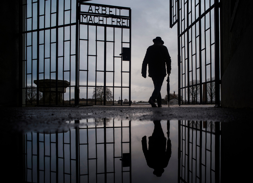 FILE - A man walks through the gate of the Sachsenhausen Nazi death camp with the phrase 'Arbeit macht frei' (work sets you free) at the International Holocaust Remembrance Day, in Oranienburg, about 30 kilometers, (18 miles) north of Berlin, Germany, Jan. 27, 2019. (AP Photo/Markus Schreiber, File)
