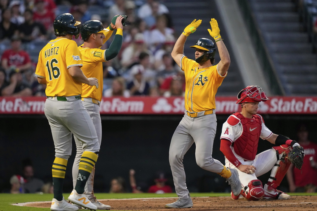 Athletics' Colby Thomas, second from right is congratulated by Nick Kurtz, left, and Brent Rooker, second from left, as Los Angeles Angels catcher Logan O'Hoppe kneels at the plate during the second inning of a baseball game Saturday, Sept. 6, 2025, in Anaheim, Calif. (AP Photo/Mark J. Terrill)