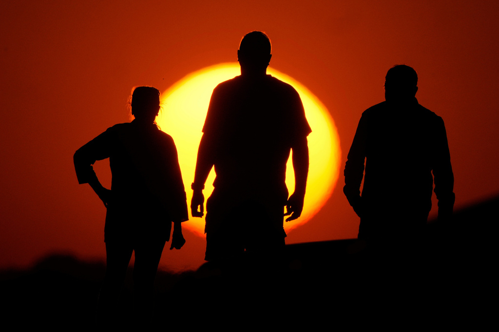 FILE - People watch the sunset from the Liberty Memorial grounds in Kansas City, Mo., May 12, 2025. (AP Photo/Charlie Riedel, File)