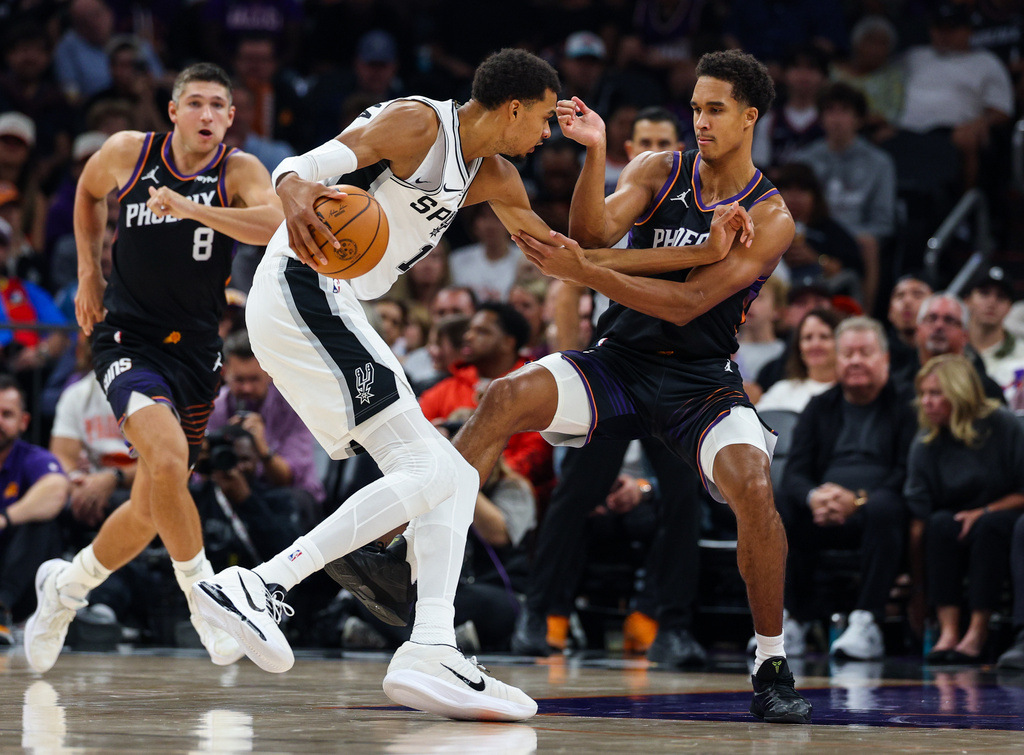 Phoenix Suns forward Oso Ighodaro, right, guards against San Antonio Spurs forward Victor Wembanyama (1) during the first half of an NBA basketball game, Sunday, Nov 2, 2025, in Phoenix. (AP Photo/Mike Christy)