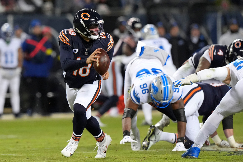 Chicago Bears quarterback Caleb Williams (18) runs from Detroit Lions linebacker al-Quadin Muhammad (96) during the second half of an NFL football game, Sunday, Jan. 4, 2026, in Chicago. (AP Photo/Nam Y. Huh)