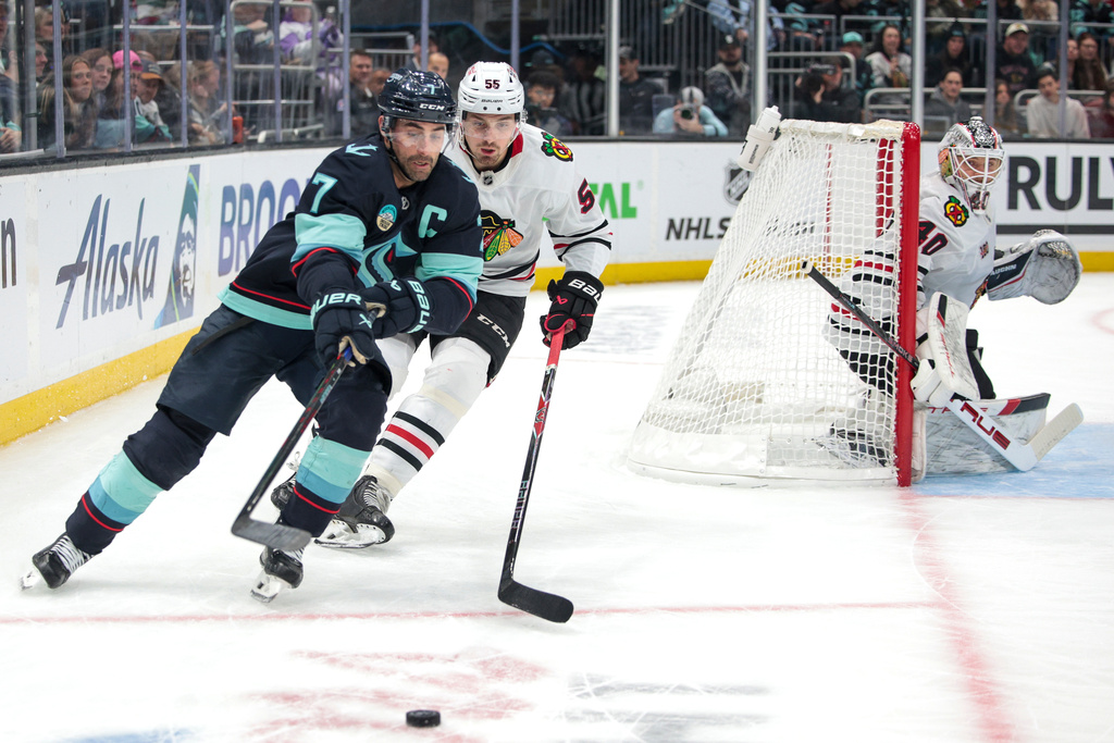 Seattle Kraken right wing Jordan Eberle (7) and Chicago Blackhawks defenseman Artyom Levshunov (55) compete for the puck as goalie Arvid Soderblom (40) looks on during the first period of an NHL hockey game Monday, Nov. 3, 2025, in Seattle. (AP Photo/Jason Redmond)