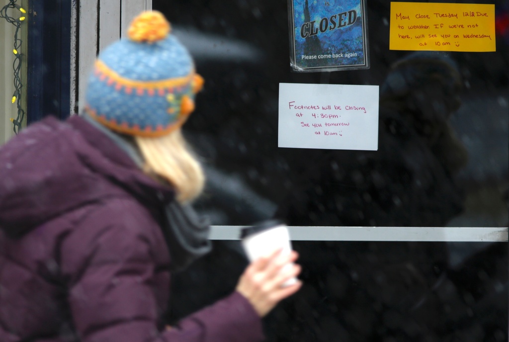 A person walks past a business that closed due to snow in Portsmouth, N.H., Tuesday, Dec. 2, 2025. (AP Photo/Caleb Jones)