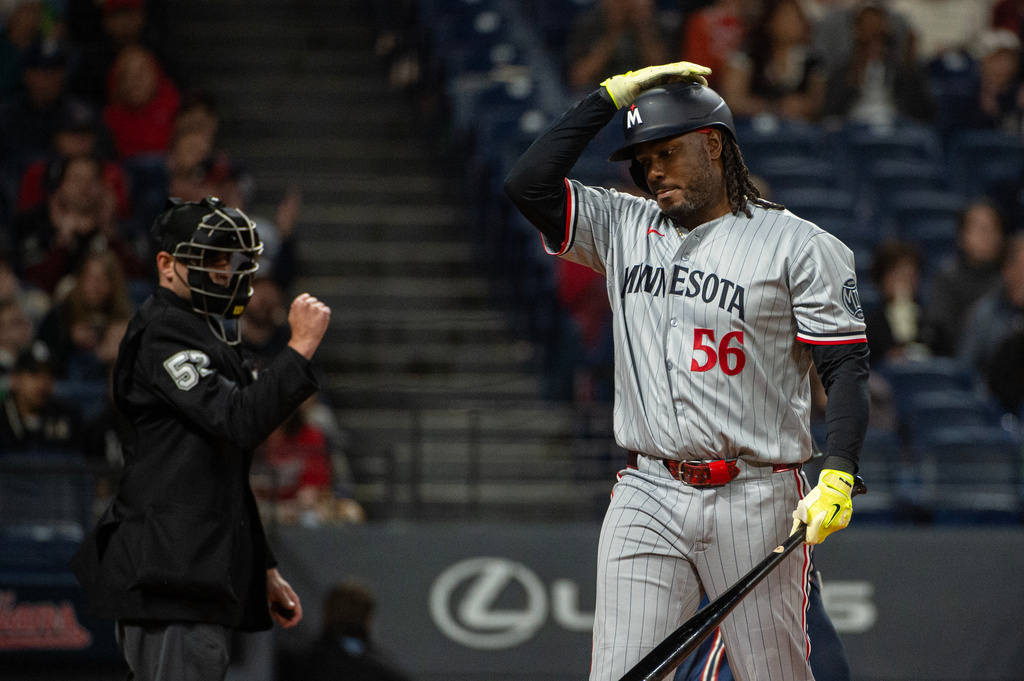 Minnesota Twins' Josh Bell (56) walks back to the dugout after striking out against Cleveland Guardians starting pitcher Tanner Bibee as umpire Paul Clemons, left, makes the call during the fourth inning of a baseball game, Saturday, May 9, 2026, in Cleveland. (AP Photo/Phil Long) CORRECTION