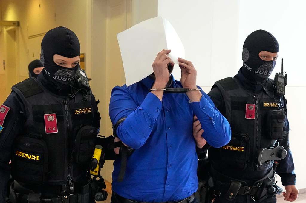 Defendant Beran A. is hiding his face behind file folders when he is escorted out of the courtroom in the District Court in Wiener Neustadt, Austria, where he stands trial for plotting to carry out an attack on one of superstar singer Taylor Swift's concerts in Vienna in August 2024 and pledging allegiance to the Islamic State group, Tuesday, April 28, 2026. (AP Photo/Matthias Schrader)