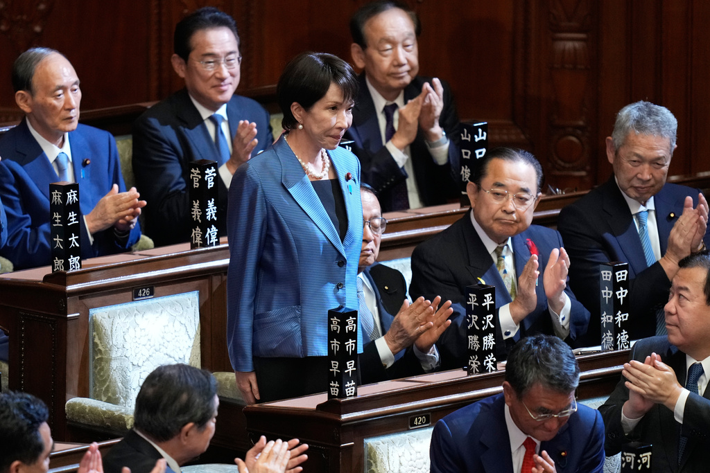 Lawmakers applaud as Sanae Takaichi, standing, was elected as Japan's new prime minister during the extraordinary session of the lower house, in Tokyo, Japan, Tuesday, Oct. 21, 2025.(AP Photo/Eugene Hoshiko)