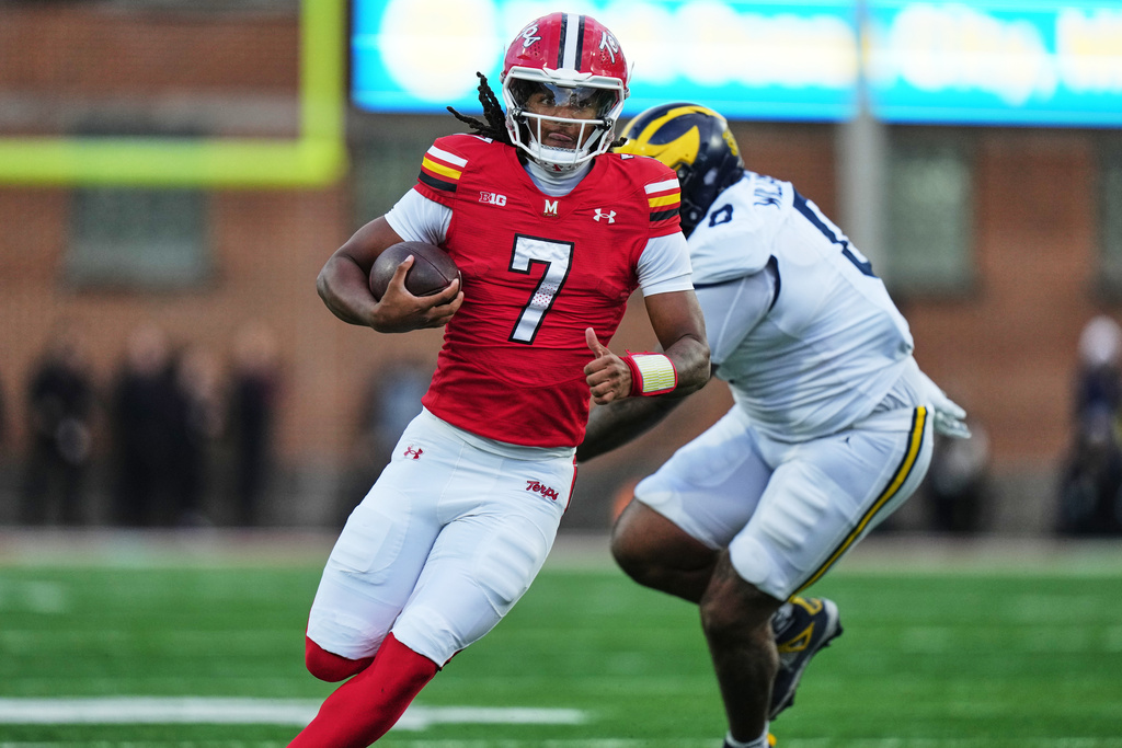 Maryland quarterback Malik Washington (7) runs the ball past Michigan defensive tackle Tré Williams (0) during the first half of an NCAA college football game, Saturday, Nov. 22, 2025, in College Park, Md. (AP Photo/Stephanie Scarbrough)
