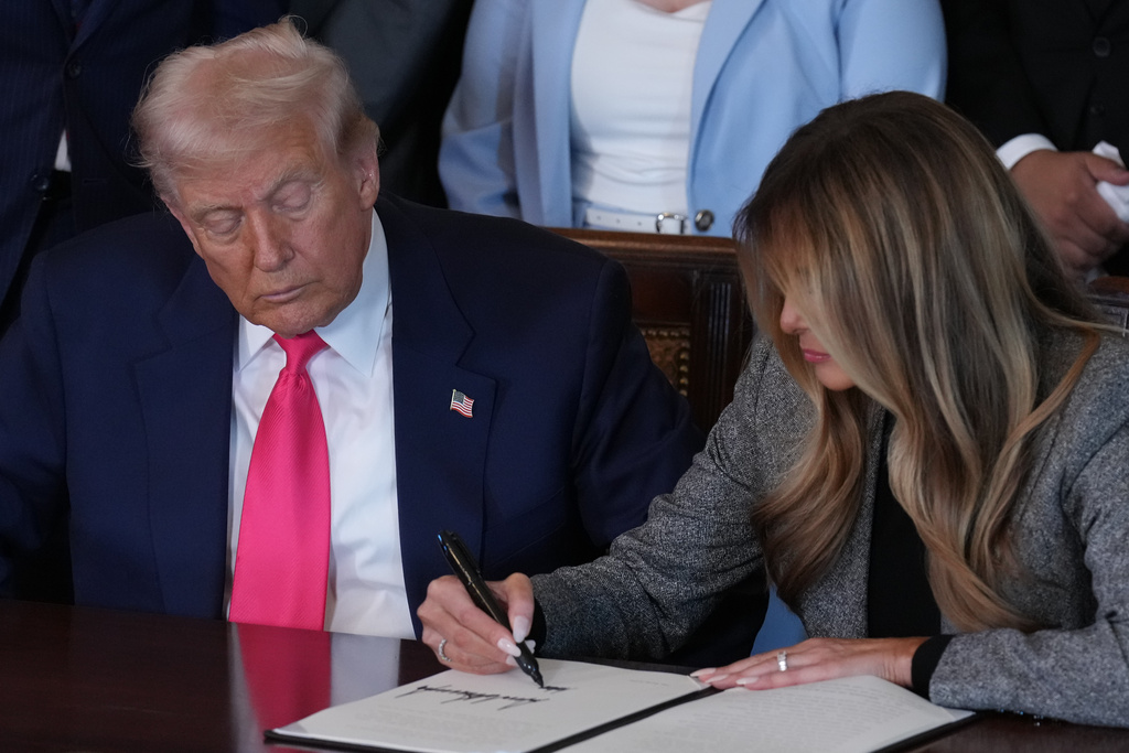 President Donald Trump watches as first lady Melania Trump adds her signature to an executive order during an event on foster care in the East Room of the at the White House, Thursday, Nov. 13, 2025, in Washington. (AP Photo/Jacquelyn Martin)