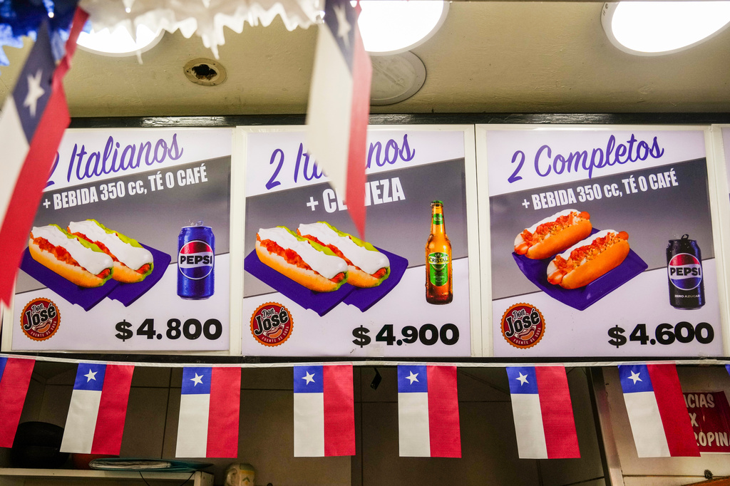 Chilean flags decorate a menu board offering combo deals for "completos," traditional Chilean hot dogs topped with mashed avocado, diced tomatoes and mayonnaise, in downtown Santiago, Chile, Thursday, Sept. 10, 2026. (AP Photo/Esteban Félix)