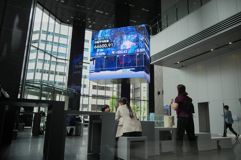 People gather in front of an electronic stock board showing Japan's Nikkei index at a securities firm Tuesday, June 2, 2026, in Tokyo. (AP Photo/Eugene Hoshiko)