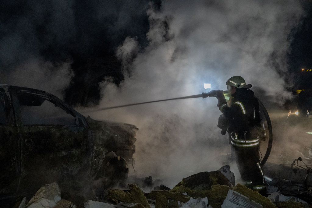 Rescue workers put out a fire of a residential building damaged by a Russian strike in Kharkiv, Ukraine, late Sunday, Nov. 23, 2025. (AP Photo/Andrii Marienko)