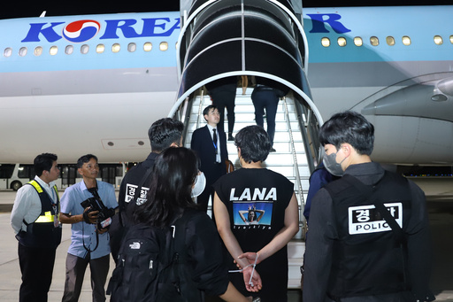 In this photo released by Agence Kampuchea Press (AKP), ons of South Koreans allegedly involved in online scams, center, is escorted by their police officers before boarding a plane at Techo International Airport in Kandal province, Cambodia, Friday, Oct. 17, 2025. (AKP via AP) In this photo released by Agence Kampuchea Press (AKP), ons of South Koreans allegedly involved in online scams, center, is escorted by their police officers before boarding a plane at Techo International Airport in Kandal province, Cambodia, Friday, Oct. 17, 2025. (AKP via AP)