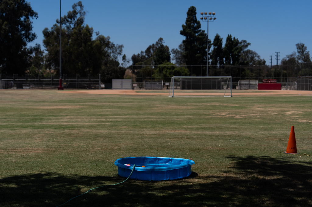A small plastic pool is filled with water for children to cool off on a soccer field in Los Angeles, Friday, July 31, 2026. (AP Photo/Jae C. Hong)