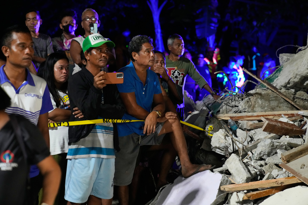 Residents look as rescuers search for survivors at a collapsed building, Wednesday, Oct. 1, 2025 after a strong earthquake struck Bogo city, Cebu Province, Central Philippines. (AP Photo/Aaron Favila)