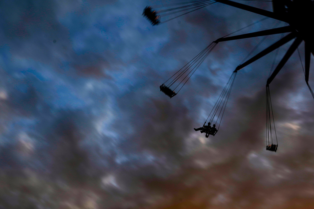 People enjoy a ride at an amusement park at sunset in Panama City, Thursday, March 19, 2026. (AP Photo/Matias Delacroix)