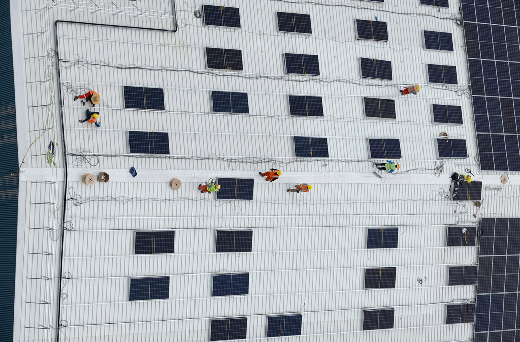 FILE - A group of workers installs solar panels on the roof of a warehouse near Jurong Island in Singapore on Oct. 6, 2025. (AP Photo/Anton L. Delgado, File)