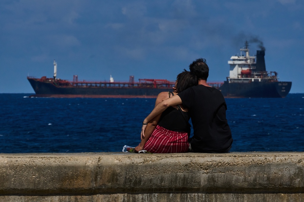 A couple sit on a seawall while watching a tanker ship exit Havana, Cuba, Saturday, Feb. 14, 2026. (AP Photo/Ramon Espinosa)