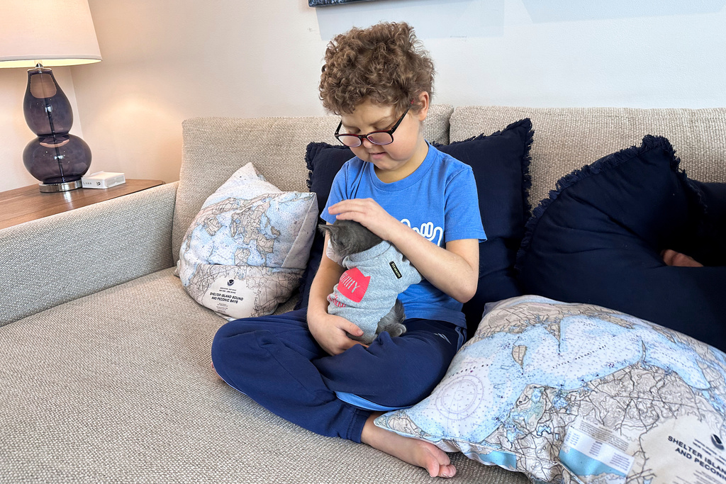 Logan Coyle, 9 years old, pets a cat that accompanied friends visiting his home, Feb. 10, 2026, in Port Washington, N.Y. (AP Photo/Phil Marcelo)