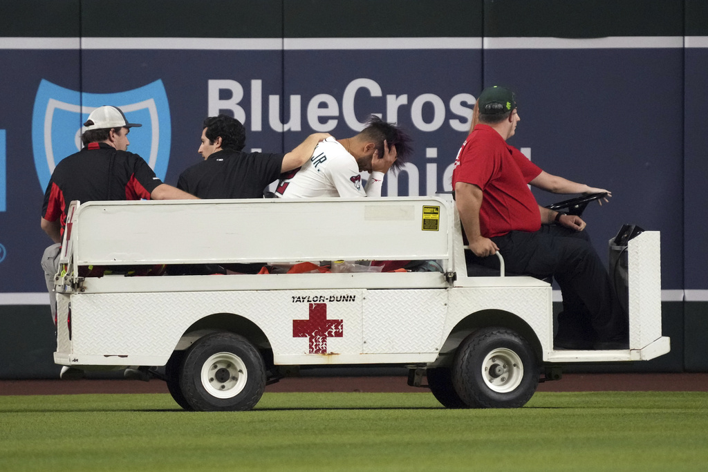 Arizona Diamondbacks' Lourdes Gurriel Jr., third from left, is taken out on a cart after diving for a ball hit by Texas Rangers' Rowdy Tellez in the sixth inning of a baseball game, Monday, Sept. 1, 2025, in Phoenix. (AP Photo/Rick Scuteri)