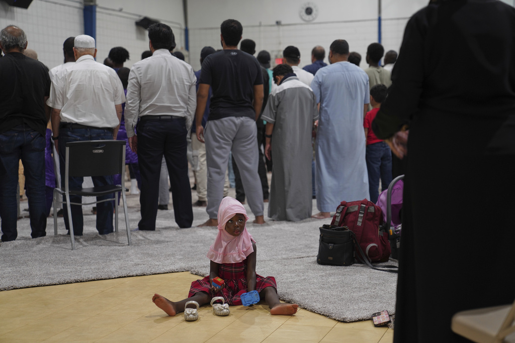 A young girl watches as men and women pray at the Islamic Center of Cedar Rapids on Friday, Aug. 8, 2025, in Cedar Rapids, Iowa. (AP Photo/Jessie Wardarski)