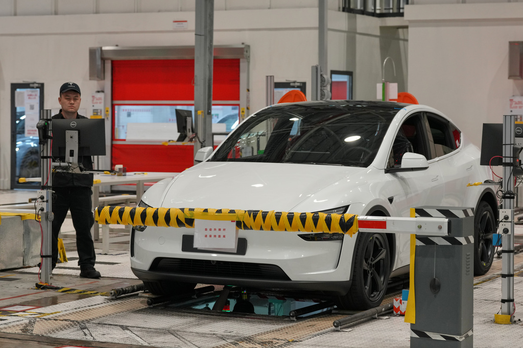 Workers inspect a Tesla Model Y at the production lines at the Tesla Gigafactory assembly plant during a media organized tour, in Shanghai, China, Tuesday, April 14, 2026. (AP Photo/Andy Wong)
