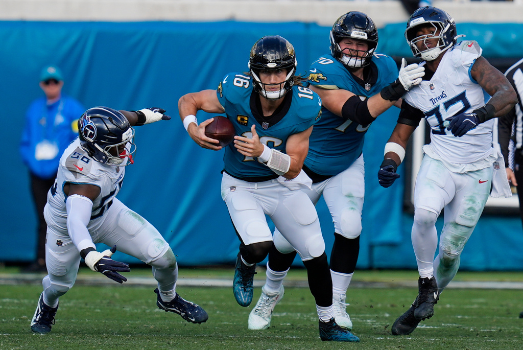 Jacksonville Jaguars quarterback Trevor Lawrence (16) runs the ball past Tennessee Titans outside linebackers Truman Jones (56) and Jaylen Harrell, far right, during the second half of an NFL football game Sunday, Jan. 4, 2026, in Jacksonville, Fla. (AP Photo/John Raoux)