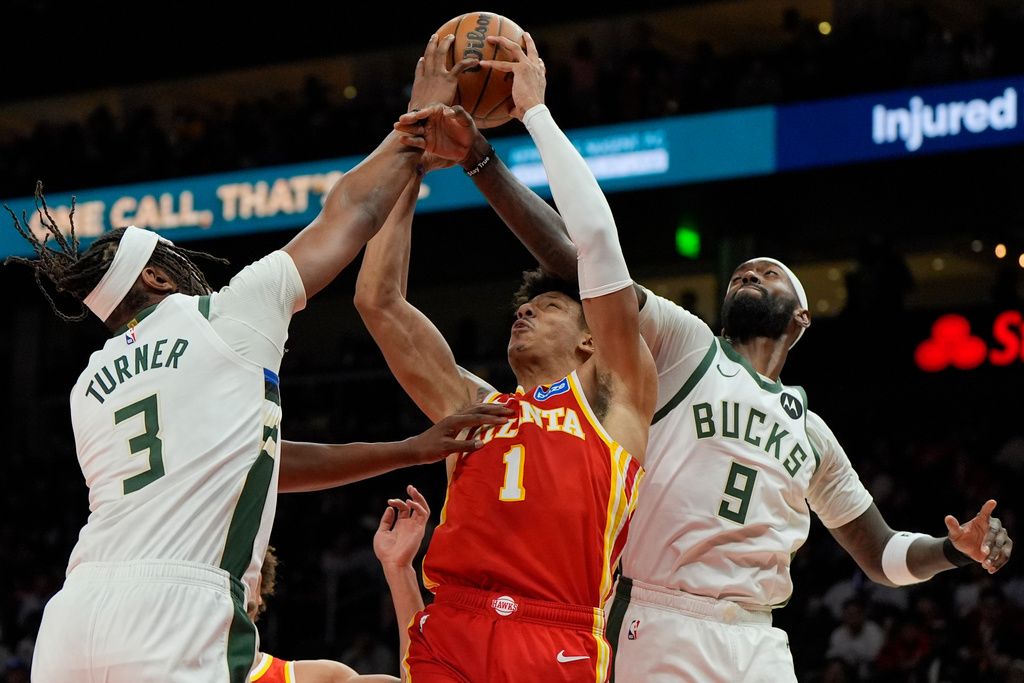 Atlanta Hawks forward Jalen Johnson (1) shoots against Milwaukee Bucks' Myles Turner (3) and Bobby Portis (9) during the second half of an NBA basketball game, Saturday, March 14, 2026, in Atlanta. (AP Photo/Mike Stewart)
