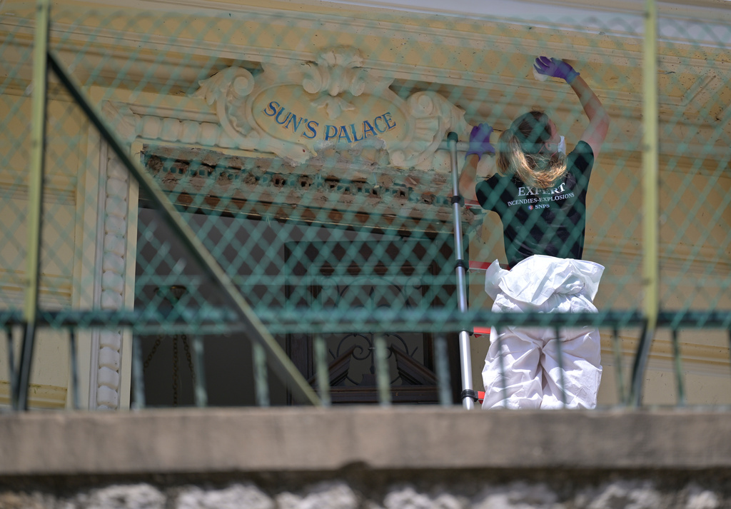 An investigator examines the scene at the residential building where an explosive device seriously injured three people a day before, in Monaco, Tuesday, June 30, 2026. (AP Photo/Philippe Magoni)