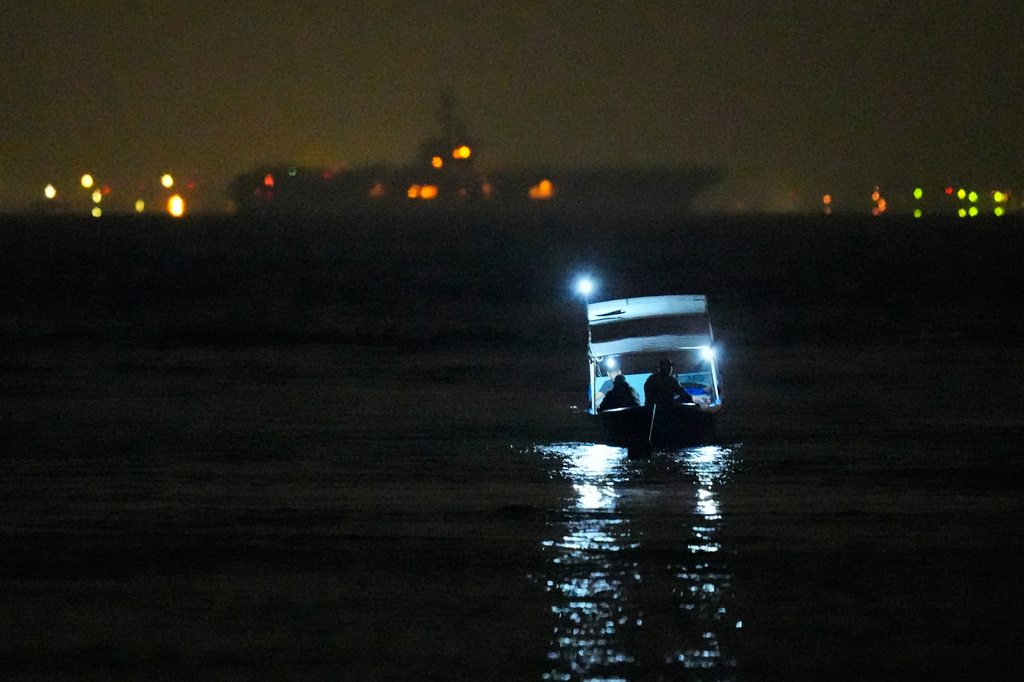 Fishermen sit in their boat as the the U.S. Navy aircraft carrier USS Abraham Lincoln is seen in the background in Batam, Indonesia, Sunday, Aug. 30, 2026. (AP Photo/Dita Alangkara)