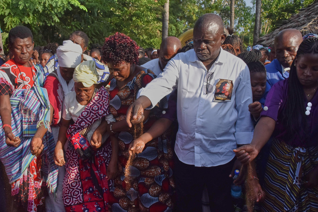 Nixon Charo, father of 29 years old Penina Zawadi, who died from complications while giving birth, casts a handful of soil into her grave during her funeral in Kilifi County, Kenya, Saturday, July 18, 2026. (AP Photo/Brian Wachira)