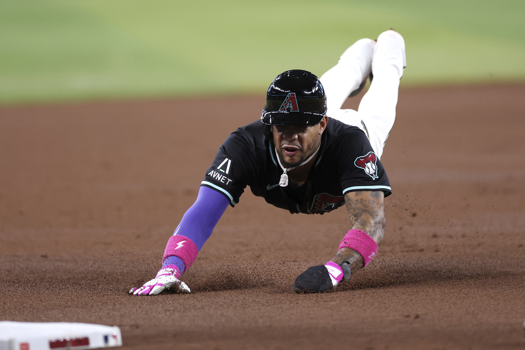 Arizona Diamondbacks' Ketel Marte slides safely into third base after a hit by Geraldo Perdomo against the Colorado Rockies during the first inning of a baseball game Saturday, Aug. 9, 2025, in Phoenix. (AP Photo/Chris Coduto)