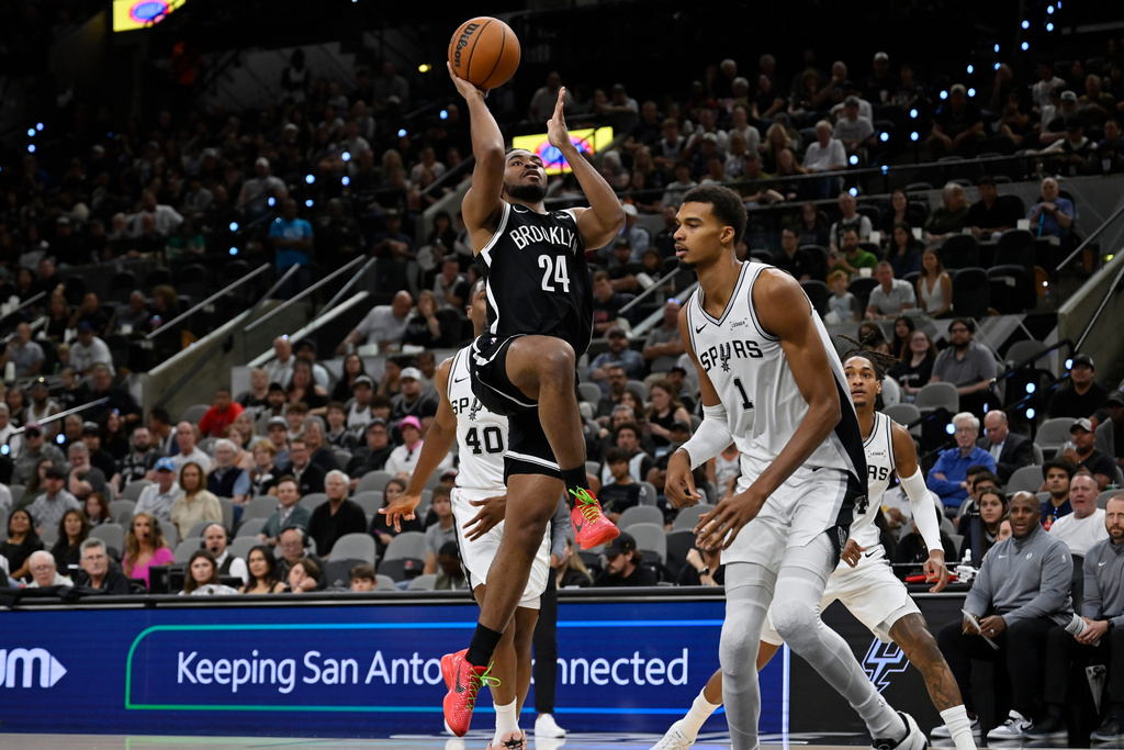 Brooklyn Nets guard Cam Thomas (24) shoots against San Antonio Spurs center Victor Wembanyama (1) during the first half of an NBA basketball game, Sunday, Oct. 26, 2025, in San Antonio. (AP Photo/Darren Abate)