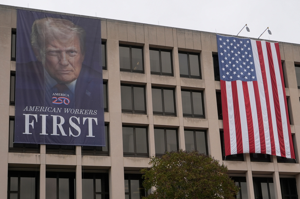 A banner with an image of President Donald Trump hangs outside the U.S. Department of Labor, Oct. 14, 2025, in Washington. (AP Photo/Carolyn Kaster)
