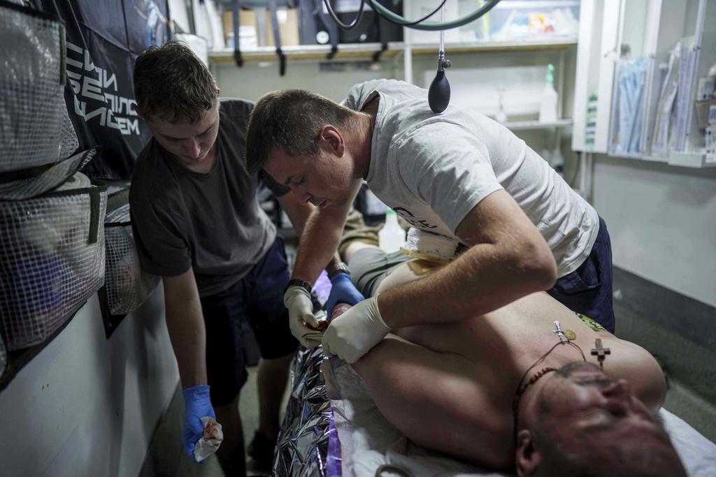 A Ukrainian military medic of 59th brigade treats his injured comrade at a stabilisation point not far from the frontline on Pokrovsk direction, Ukraine, on Friday, Aug. 8, 2025. (AP Photo/Evgeniy Maloletka)