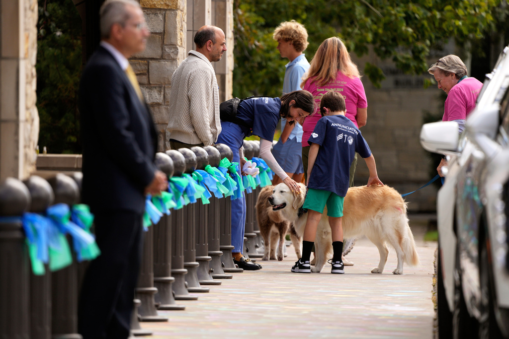 Attendees are greeted by support dogs outside of Mt. Olivet Lutheran Church for the funeral of 8-year-old Fletcher Merkel, who was killed in a school church shooting, in Minneapolis, Sunday, Sept. 7, 2025. (Jeff Wheeler/Star Tribune via AP)