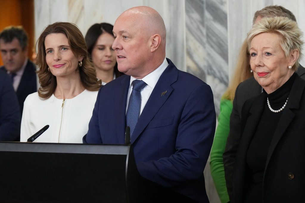 New Zealand Prime Minister Christopher Luxon, center, speaks to reporters at Parliament in Wellington, New Zealand, on Wednesday, Aug. 12 2026, after a leadership vote among his own party’s lawmakers. (AP Photo/Charlotte Graham-McLay)